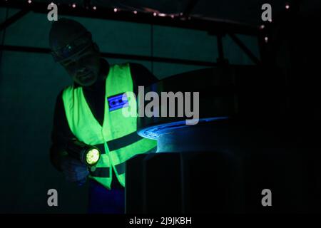 Kehl, Deutschland. 28. April 2022. Patrick Decouval, ein Mitarbeiter der Herrenknecht AG Rebuild Services in Kehl, inspiziert ein Antriebsritzel mittels Fluoreszenzeindringprüfung. Hier zerlegt der Tunnelbohrmaschinenhersteller alte Maschinen in ihre Einzelteile, konditioniert sie und montiert sie wieder. (To dpa 'alt in neu verwandeln - wo Tunnelbohrmaschinen auseinandergerissen werden') Quelle: Benedikt Spether/dpa/Alamy Live News Stockfoto