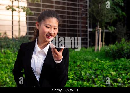 Asiatische Frau, die Sprachnachricht mit dem Telefon aufzeichnet Stockfoto