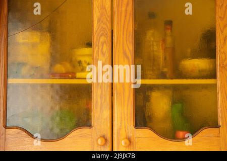 Alte braune hölzerne Küchenschrank mit Glastüren in der Küche zu Hause, Küchenmöbel und Schränke Stockfoto