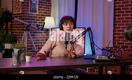 Selektiver Fokus auf digitale Videokamera Bildschirmaufnahme kaukasischen Vlogger im Gespräch mit Publikum aus Hause Podcasting Studio. Frau Influencer, die sich selbst dabei filmt, Live-Übertragungen für soziale Medien zu machen. Stockfoto