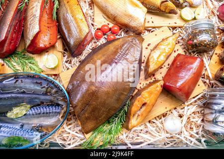 Geräucherter Heilbutt und Pfeffer, Zitrone und Rosmarin auf Holzschneidebrett Draufsicht. Verschiedene geräucherte und gesalzene Fische im Seafood Shop. Fischhintergrund. Stockfoto