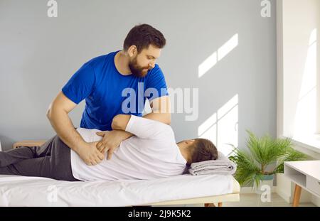 Chiropraktiker, Physiotherapeut, Osteopath oder manuelle Therapeut helfen Mann mit Rückenproblemen Stockfoto