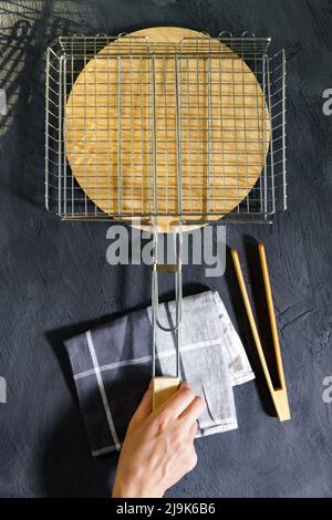 Leerer sauberer Metallgrill zum Grillen auf einem Picknick. Draufsicht, dunkler Hintergrund. Vertikales Foto Stockfoto