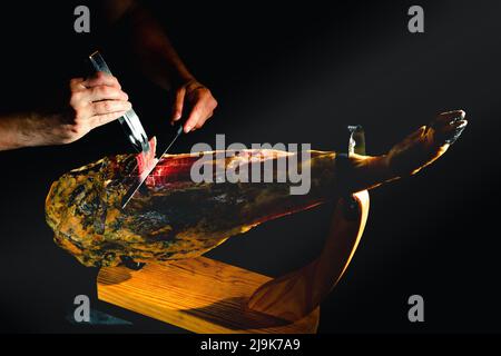 Schneiden von spanischem íberic Schinken. Spanischer Jamon und traditionelles Essen. Trockener spanischer Schinken, Jamon Serrano, Bellota, italienischer Prosciutto Crudo oder Parmaschinken. Stockfoto