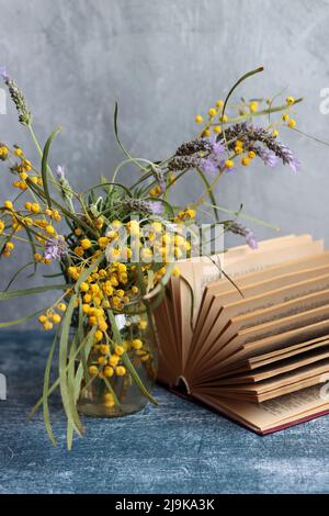 Frühlingsblumen in einem Glas. Einfache Komposition Stillleben mit Akazie und Lavendelblüten. Hellgrauer Hintergrund mit Kopierbereich. Stockfoto