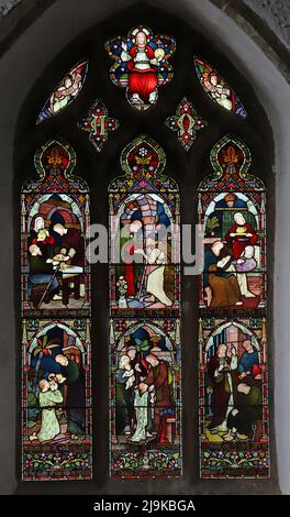 Ein Buntglasfenster von Frederick Preedy, das 6 Acts of Corporal Mercy, Saints Peter and Paul Church, King's Sutton, Northamptonshire, darstellt Stockfoto