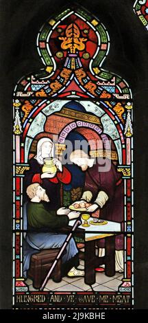 Ein Buntglasfenster von Frederick Preedy, das Corporal Acts of Mercy, St Peter and St Paul's Church, King's Sutton, Northamptonshire, zeigt Stockfoto