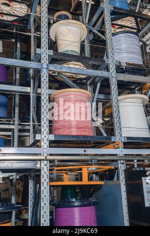 Farbiger Kabelaufwicklung auf Spulen. Metallregale mit farbigen Kabelspulen im Werk. Stockfoto