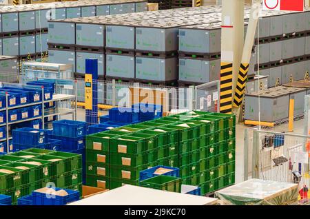 Industrieller Vertrieb, Zusammensetzung. Lagerung mit hohen Fachböden, Ladeboxen in Regalen. Reihen von Regalen mit Kunststoffkästen im Werk. Stockfoto