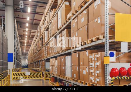 Industrieller Vertrieb, Zusammensetzung. Lagerung mit hohen Fachböden, Ladeboxen in Regalen. Reihen von Regalen mit Kästen im Werk. Stockfoto