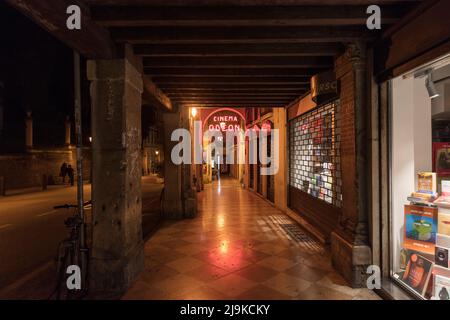Neonschild für Kino in der Arkade von Geschäften Corso Andrea Palladio. UNESCO-Weltkulturerbe Vicenza bei Nacht. Stockfoto