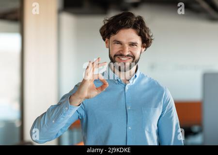 Porträt eines lächelnden Geschäftsmanns, der eine gute Geste zeigt Stockfoto