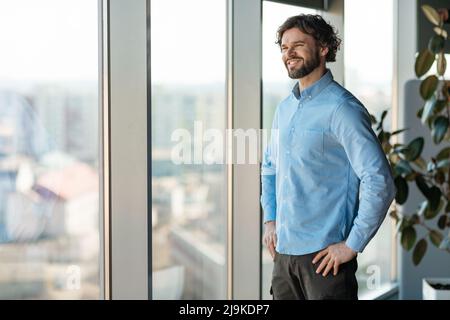 Porträt eines lächelnden Geschäftsmanns, der auf das Fenster schaut Stockfoto