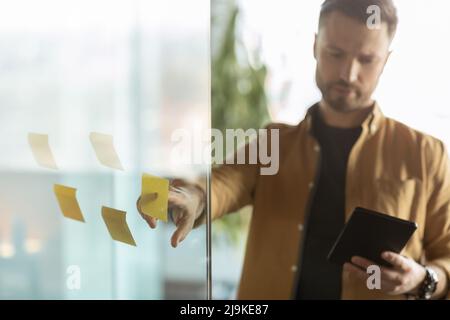 Geschäftsmann Zeigt Auf Haftnotiz An Glaswand Im Büro Stockfoto