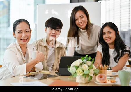 Ein Porträt einer Gruppe verschiedener Geschäftsleute, die im Büro oder Besprechungsraum mit positivem Ausdruck zusammensitzt. Konzept der geschäftlichen Teamarbeit Stockfoto