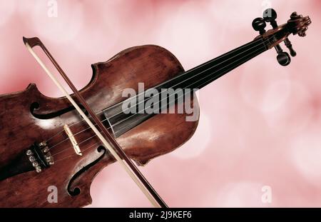 Detail eines Violin- und Bogenkörpers auf rotem unscharfem Hintergrund Stockfoto