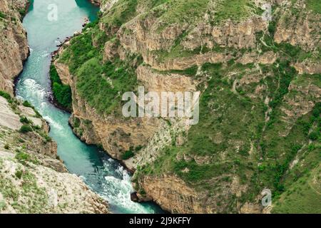 Blick von oben auf einen schnellen Gebirgsfluss, der am Fuße eines tiefen Canyons fließt Stockfoto