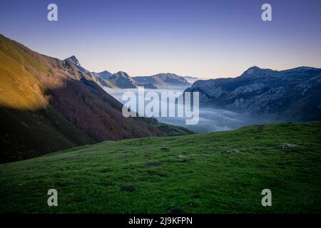 Landschaft im Morgengrauen, wo wir die Berge und das Tal des Naturparks Somiedo in Asturien, Spanien, mit niedrigen Wolken oder Nebel im Tal sehen. Idyll Stockfoto