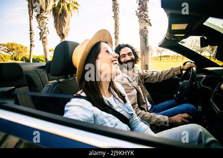 Glückliches junges Paar, das auf einer Sommerreise ein Cabriolet fährt Stockfoto