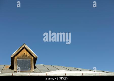 Dach des alten Hauses mit Dachfenster. Dach des Dorfhauses. Architekturdetails. Stockfoto