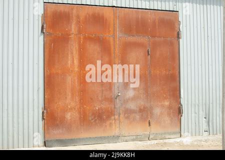 Rostige Tore. Eingang zur Werkstatt. Industrie im Detail. Rostetes Metall. Stockfoto