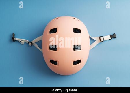 Rosa Helm auf blauem Hintergrund. Schutz vor Aktivitäten für Kinder im Freien Stockfoto