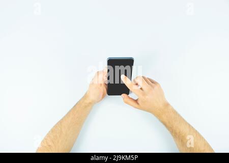 Mann Hände Surfen im Internet mit einem Mobiltelefon, schwarzem Bildschirm, Handy mit Kopierplatz, Klicken oder Berühren auf dem Bildschirm, Draufsicht Stockfoto