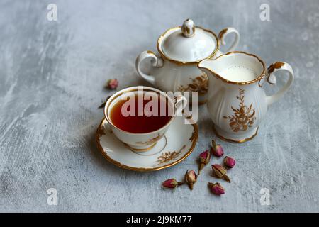 Tee mit Rosen Nahaufnahme Foto. Kräutertee in einer kleinen weißen Keramikschale auf einem Tisch. Hellgrauer Hintergrund mit Kopierbereich. Stockfoto