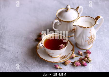 Tee mit Rosen Nahaufnahme Foto. Kräutertee in einer kleinen weißen Keramikschale auf einem Tisch. Hellgrauer Hintergrund mit Kopierbereich. Stockfoto
