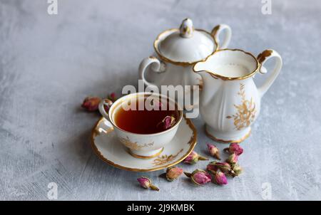 Tee mit Rosen Nahaufnahme Foto. Kräutertee in einer kleinen weißen Keramikschale auf einem Tisch. Hellgrauer Hintergrund mit Kopierbereich. Stockfoto