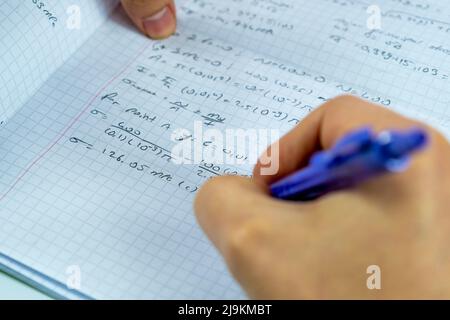 Mathematische Zahlen auf einem Notizbuch und Mann Hand halten lila Bleistift, konzentrieren sich auf Lösungsidee, Studium Mathematik Konzept, Sitzansicht Stockfoto