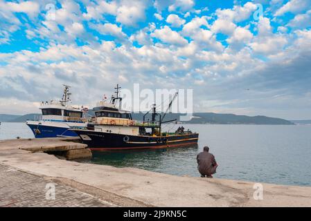 Canakkale, Türkei. 18.. Februar 2022. Türkische Fischerboote vertäuten in Canakkale auf den Dardenelles bei Gallipoli, der Westküste der Türkei. Auf der Halbinsel Gallipoli am Nordufer der Dardanelles-Meerenge im Nordwesten der Türkei finden ausgedehnte Schlachtfelder und Gedenkstätten des Ersten Weltkriegs statt, eine Kampagne zwischen dem Osmanischen Reich und den alliierten Mächten. Die Dardanelles-Straße ist eine wichtige Handelsroute, die das Mittelmeer und das Schwarze Meer verbindet, mit der Stadt Canakkale am Eingang, eine Stadt, die nicht nur für ihre historische und wichtig ist Stockfoto