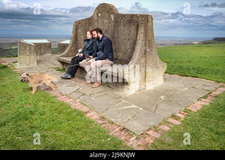 Ein Paar bietet die Aussicht vom Devil's Dyke Commemorative Seat auf den South Downs in der Nähe von Brighton. Stockfoto