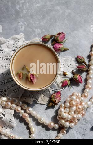 Tee mit Rosen Nahaufnahme Foto. Kräutertee in einer kleinen weißen Keramikschale auf einem Tisch. Hellgrauer Hintergrund mit Kopierbereich. Stockfoto