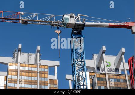 Katowice, Schlesien, Polen; März 19., 2022: Altes Wahrzeichen von Katowice - Wolkenkratzer in der Opolska-Straße mit einem Kran, der ein neues Geschäftszentrum baut Stockfoto