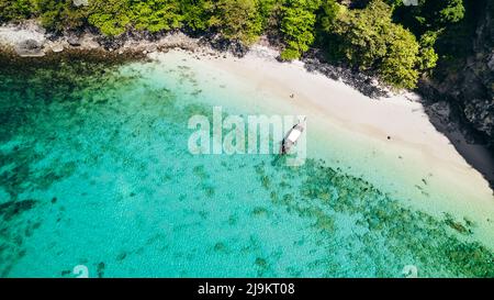 Thailändisches Longtail-Boot vor Anker an einem weißen Sandstrand auf Ko Kai (Chicken Rock Island) in Krabi Thailand mit tropischem türkisblauem Wasser und Korallenriff Stockfoto