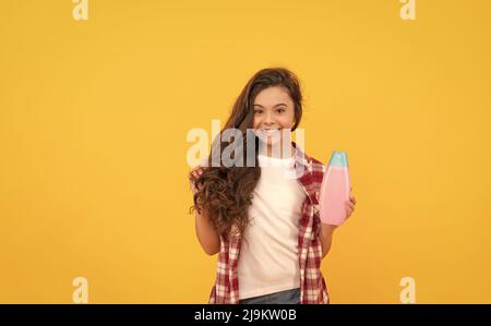 Schönheit. Kind verwenden Duschgel. Happy teen Mädchen mit Shampoo-Flasche. Haarwäsche im Salon Stockfoto