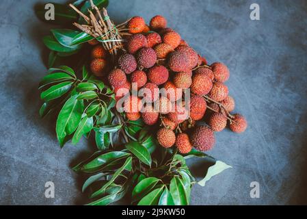 Litschi-Frucht mit grünem Blatt auf schwarzem Hintergrund, frisch reife Litschi aus Litschi-Baum bei Tropical Fruit Thailand im Sommer Stockfoto