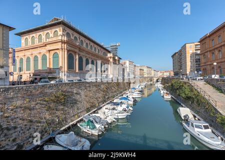 Historischer Mercato Centrale, der Zentralmarkt (links) mit Booten, die in einem Kanal festgemacht sind, umgeben von historischen Gebäuden in Livorno, Toskana, Italien Stockfoto