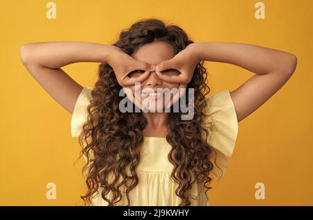 Lustiges Kind mit langen lockigen Haaren und perfekte Haut macht Gesichter, viel Spaß Stockfoto