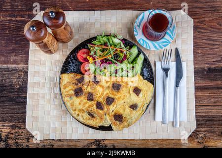 Omelette mit kavurma. Geröstet (kavurma) Omelette beliebte Türkei Essen serviert mit frischem Gemüse und Sauce auf einer Platte. Stockfoto