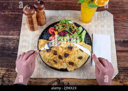 Omelette mit kavurma. Geröstet (kavurma) Omelette beliebte Türkei Essen serviert mit frischem Gemüse und Sauce auf einer Platte. Stockfoto