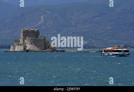 Landschaft mit Panoramablick auf ein Ausflugsboot und Bourtzi, das venezianische Schloss im Renaissance-Stil und das historische Wahrzeichen von Nafplio in Griechenland. Stockfoto