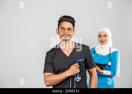 Schöne muslimische Ärztin und indische Krankenschwester in Brillen diskutieren Aufgaben. Porträt von schönen medizinischen Mitarbeitern mit Stethoskopen. Medizinische Hilfe, Insura Stockfoto