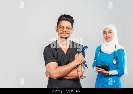 Schöne muslimische Ärztin und indische Krankenschwester in Brillen diskutieren Aufgaben. Porträt von schönen medizinischen Mitarbeitern mit Stethoskopen. Medizinische Hilfe, Insura Stockfoto