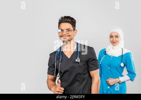 Schöne muslimische Ärztin und indische Krankenschwester in Brillen diskutieren Aufgaben. Porträt von schönen medizinischen Mitarbeitern mit Stethoskopen. Medizinische Hilfe, Insura Stockfoto