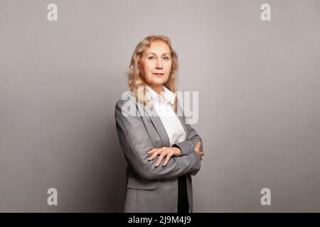 Ziemlich ältere Geschäftsfrau, erfolgreiches Vertrauen mit gekreuzten Armen Stockfoto