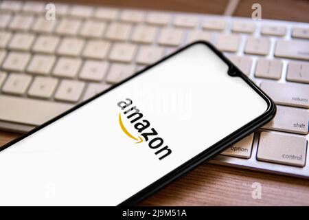 In dieser Abbildung wird ein Amazon-Logo auf einem Smartphone angezeigt, das auf einer Computertastatur platziert ist.
