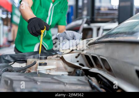 Automechaniker, der das Motoröl überprüft. Für Kunden, die das Auto für Reparaturdienste nutzen, arbeitet der Mechaniker in der Garage. Stockfoto