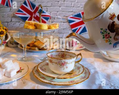 Queen Elizabeth II Platinum Jubilee Cream Tea Street Party Food rot-weiße und blaue Fahnen mit Feier Union Jack Food Toppers auf einem weißen Jahrgang Stockfoto